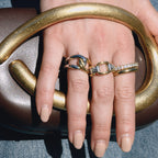 Two-tone link and crossover rings worn together on a hand