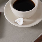 White flower ring displayed beside a coffee cup
