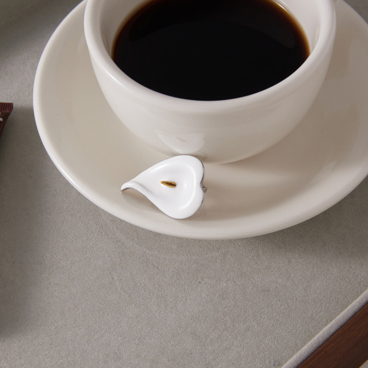 White flower ring displayed beside a coffee cup