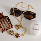 Leopard-pattern heart necklace and matching earring references arranged with styling props