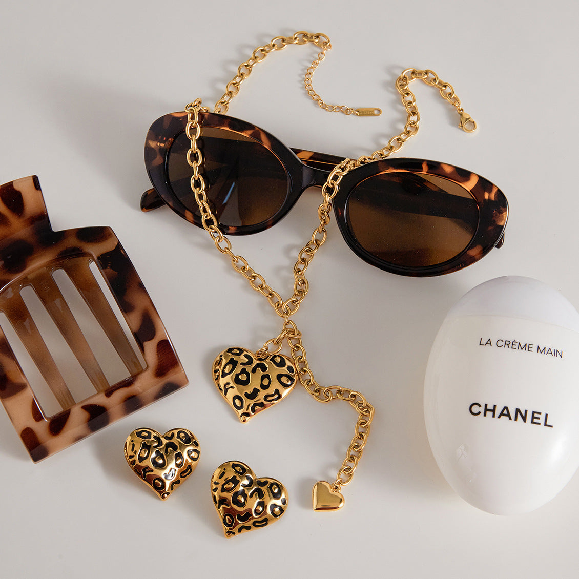 Leopard-pattern heart necklace and matching earring references arranged with styling props