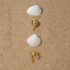 Gold-tone pointed earrings arranged on sand