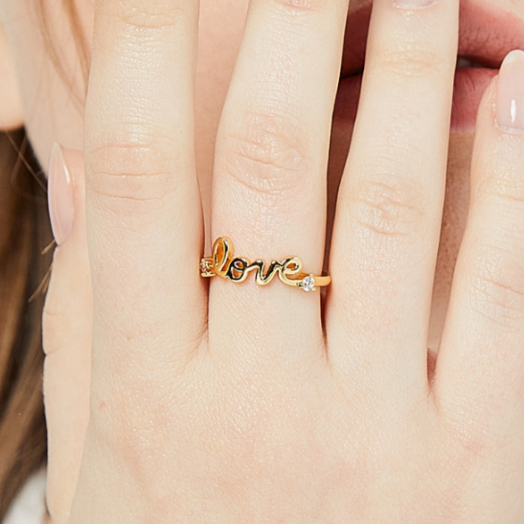 LOVE lettering ring worn on the hand with two small clear stones