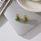 pair of marbled green resin sphere earrings on gray surface