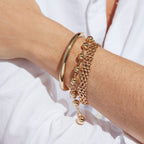 Two-tone ball bead bracelet styled with other bracelets on a wrist