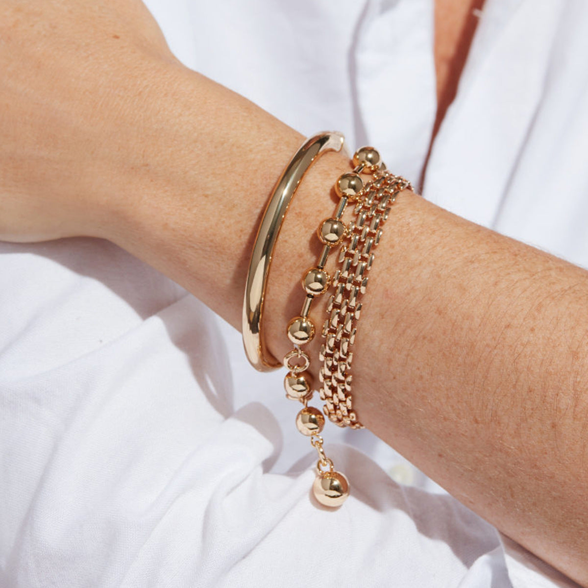 Two-tone ball bead bracelet styled with other bracelets on a wrist