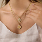 Two gold tone medallion necklaces shown at neckline