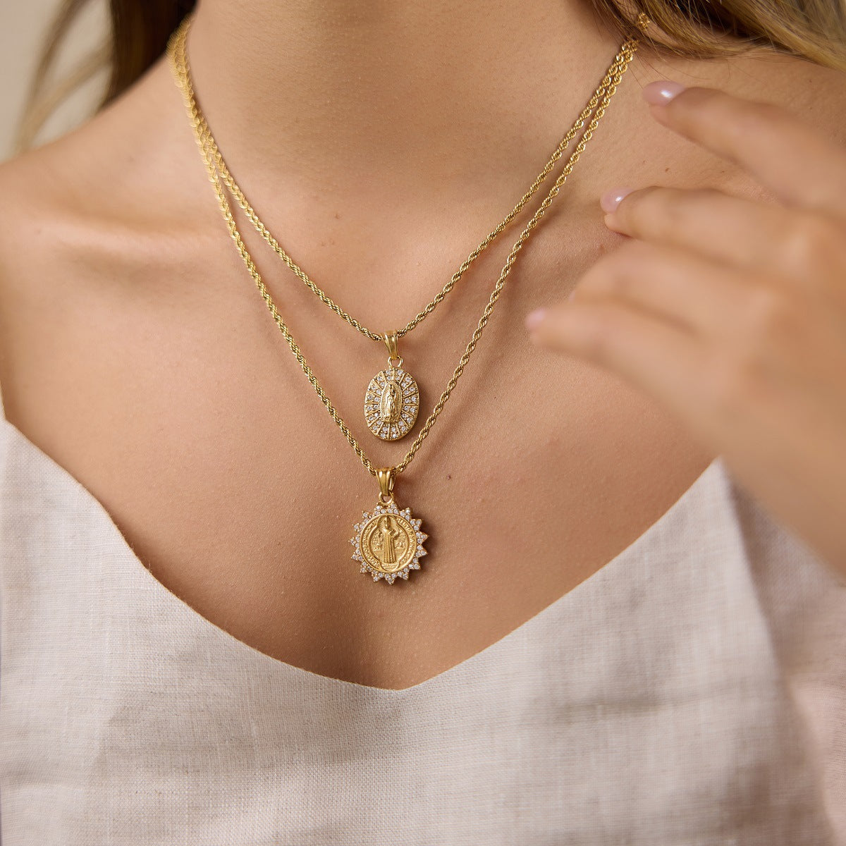 Two gold tone medallion necklaces shown at neckline