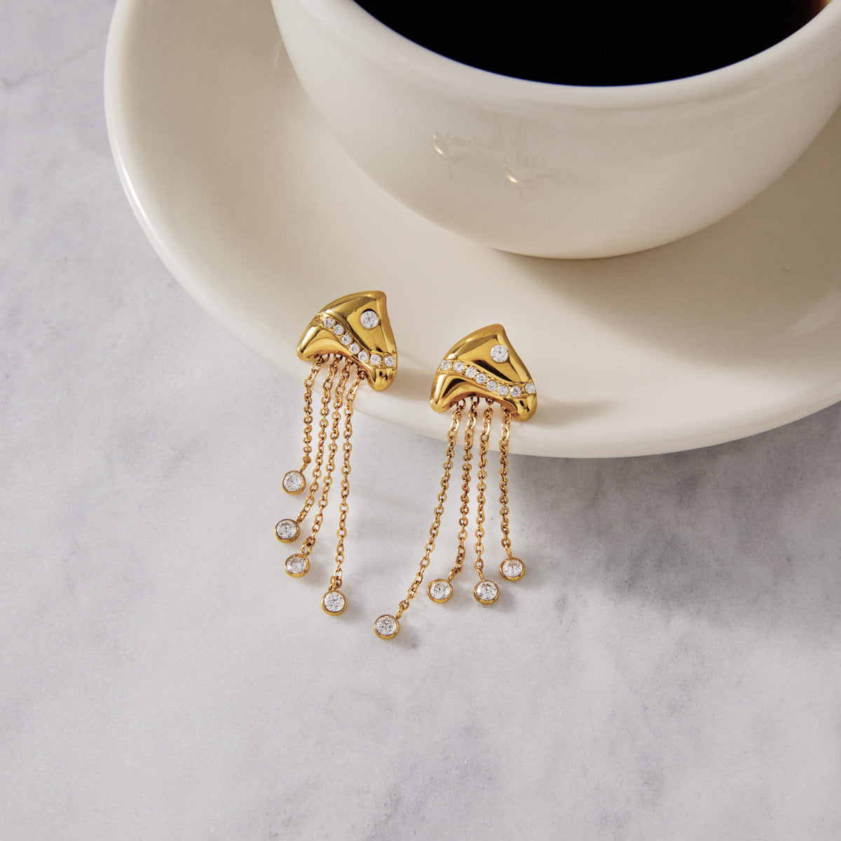 Clear-tipped tassel earrings beside a cup