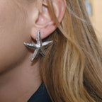 silver-finish textured starfish stud earring worn from the side