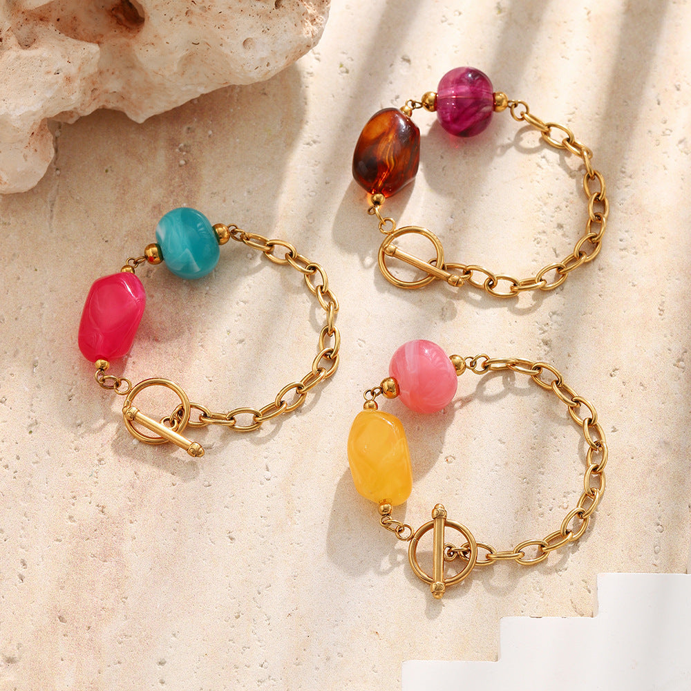 Three colorful two-bead toggle bracelets arranged on pale stone
