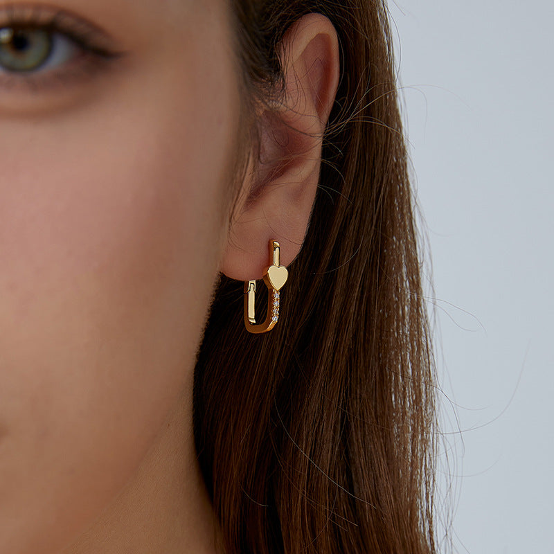gold plated heart zirconia huggie earring worn on the ear