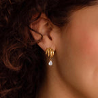 Gold tone multi-loop earring with clear teardrop on ear