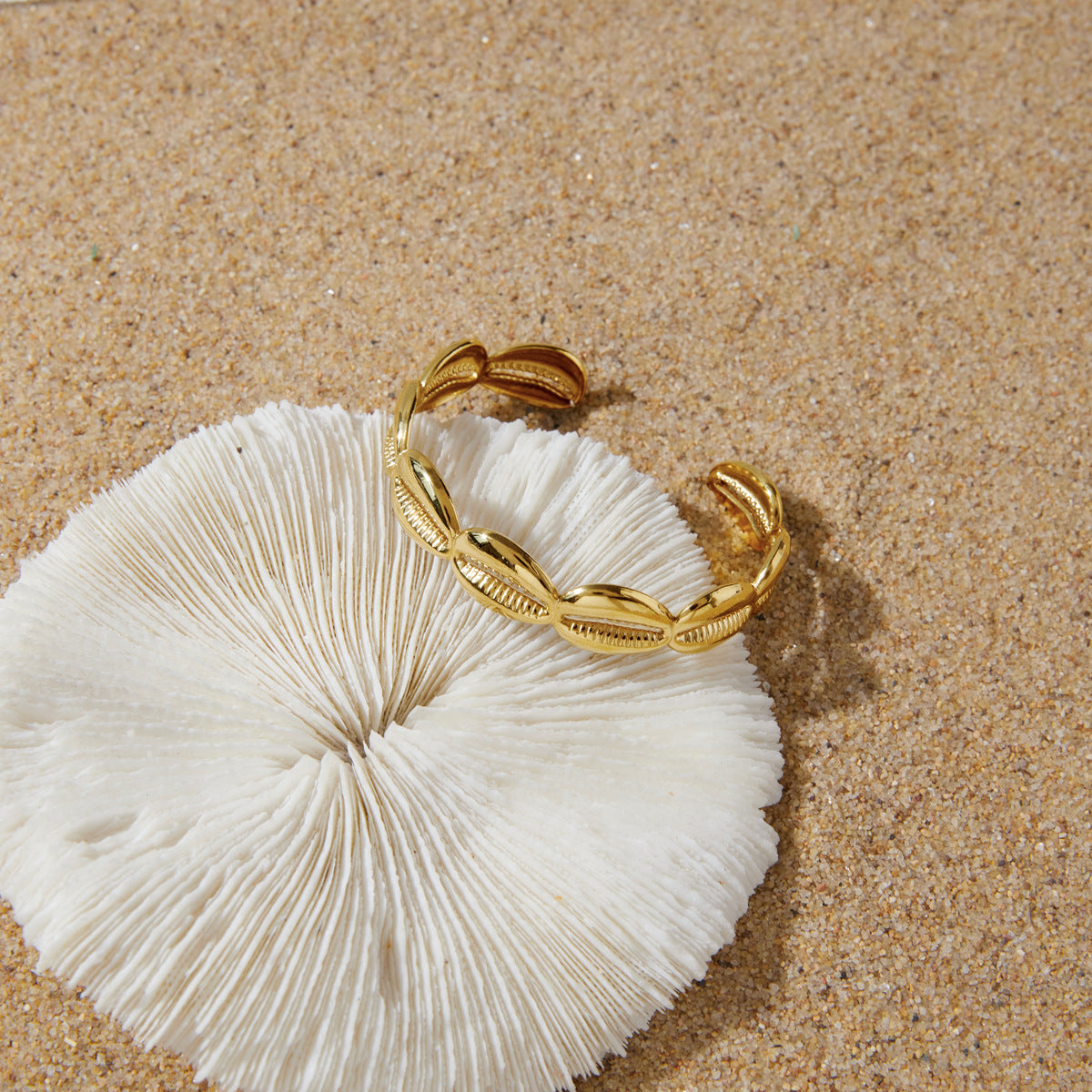 Cowrie-shell cuff on textured white surface