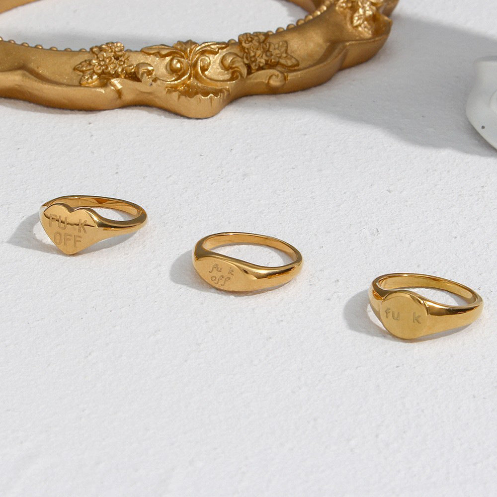 Round oval and heart signet rings beside a decorative frame