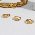 Round oval and heart signet rings beside a decorative frame