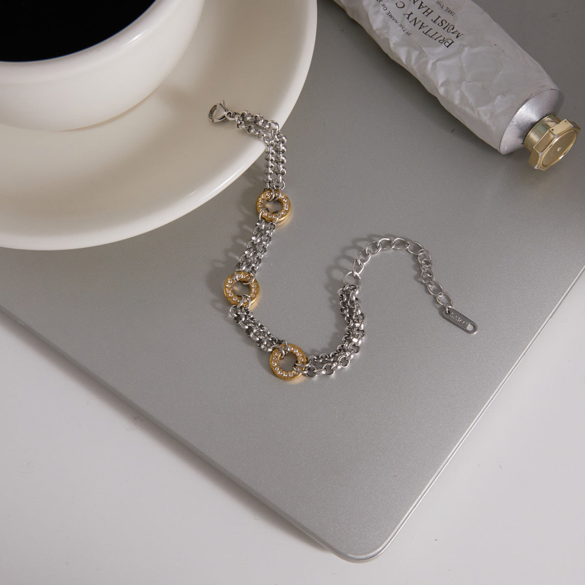 Circle-link bracelet displayed beside a cup