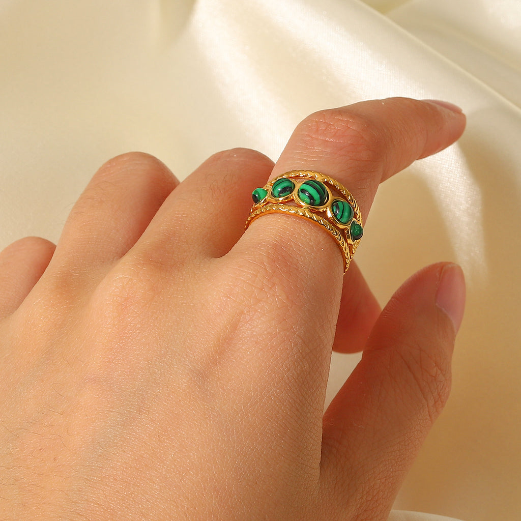 Gold plated triple green stone open ring worn on a hand
