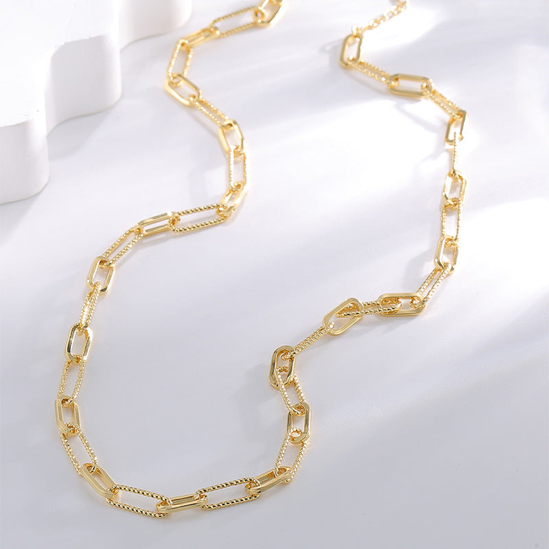 mixed-link gold plated chain necklace arranged on a white display