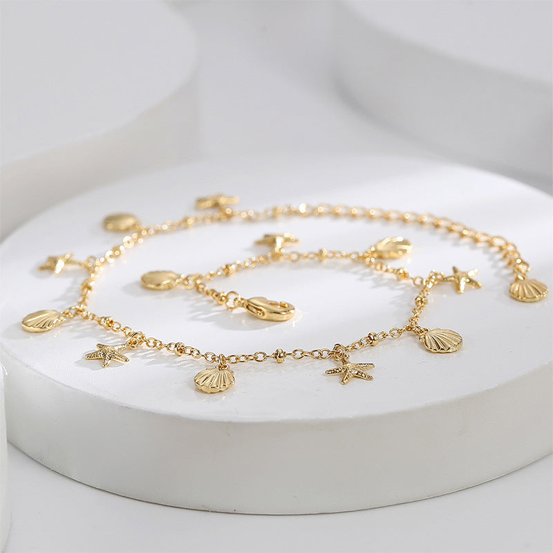 starfish and scallop charm anklet arranged on white