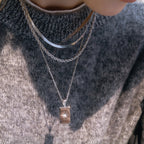 Gold plated three-strand star tag necklace worn over a knit top