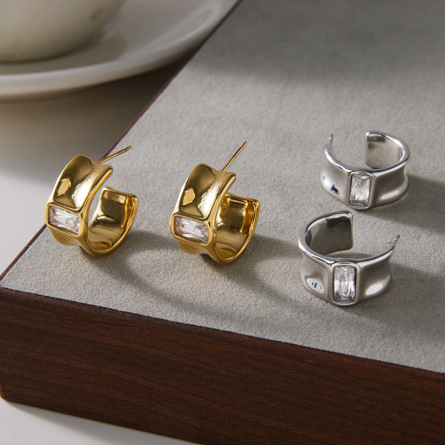 Gold and silver-tone rectangular accent open hoops on a surface