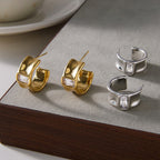 Gold and silver-tone rectangular accent open hoops on a surface