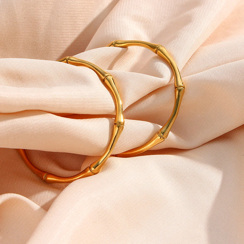 Gold plated bamboo hoops on pale fabric