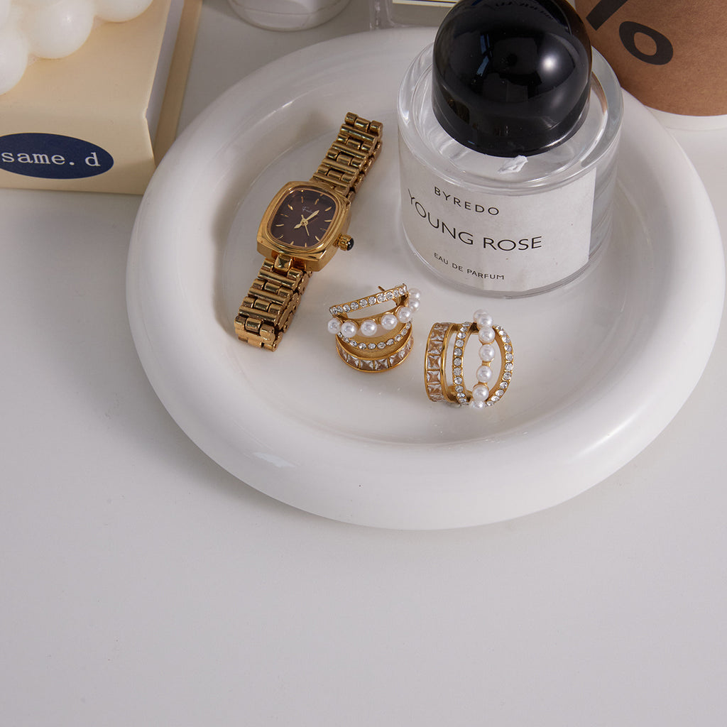 Stainless steel pearl and stone hoops arranged on a white tray
