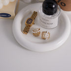Stainless steel pearl and stone hoops arranged on a white tray