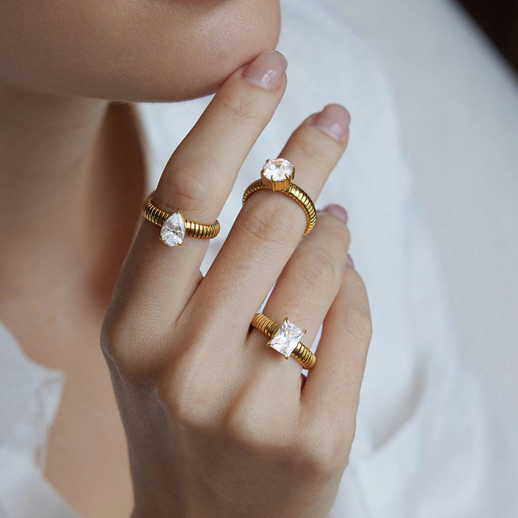 Gold-tone ribbed solitaire rings worn across three fingers