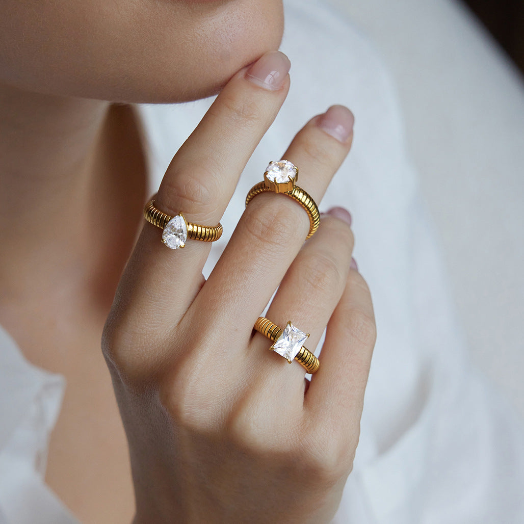 Gold-tone ribbed solitaire rings worn across three fingers