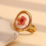 gold plated open ring with a dried red flower under a clear dome