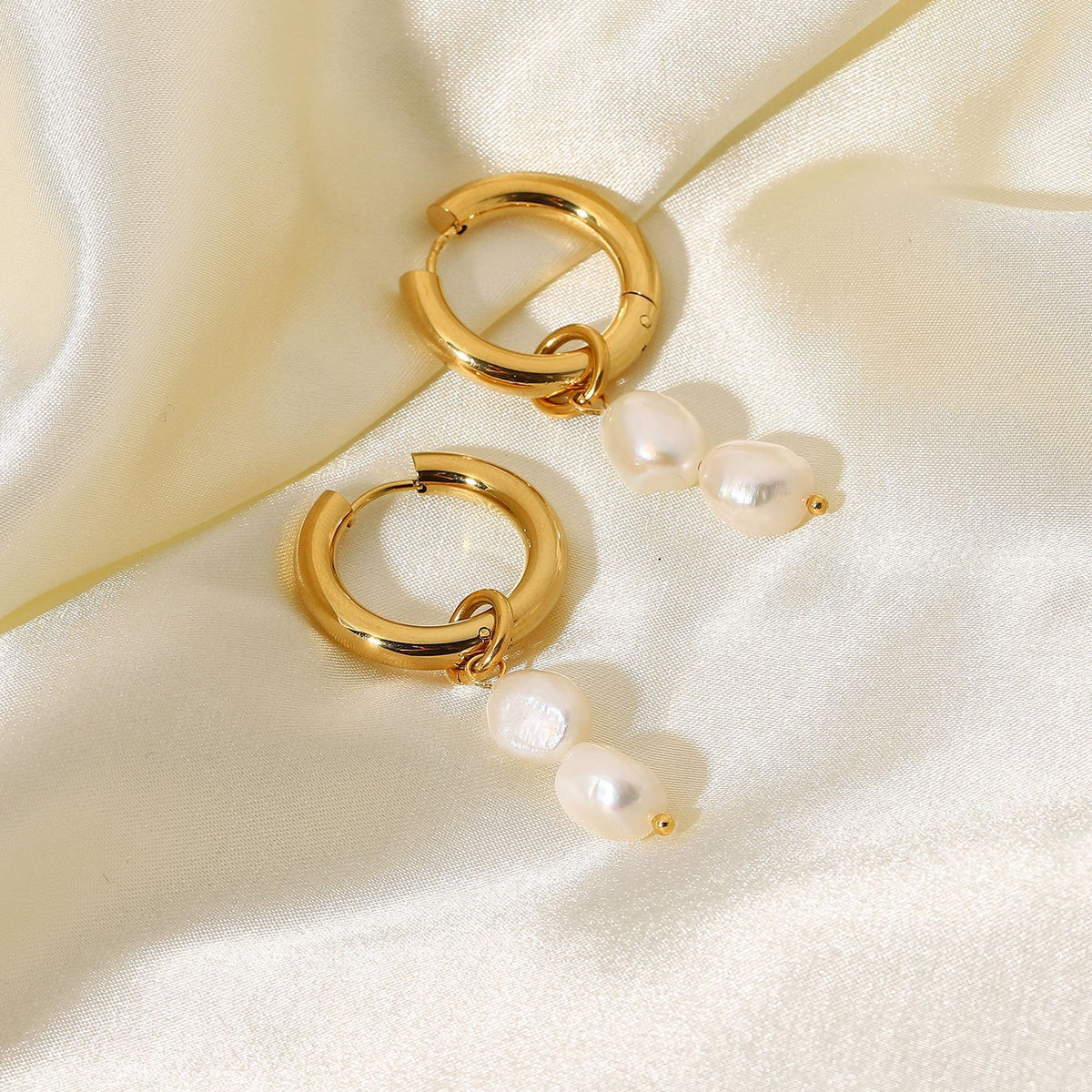 Double freshwater pearl hoops arranged on pale fabric