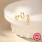 mixed floral stud and hoop earrings arranged on a cream display