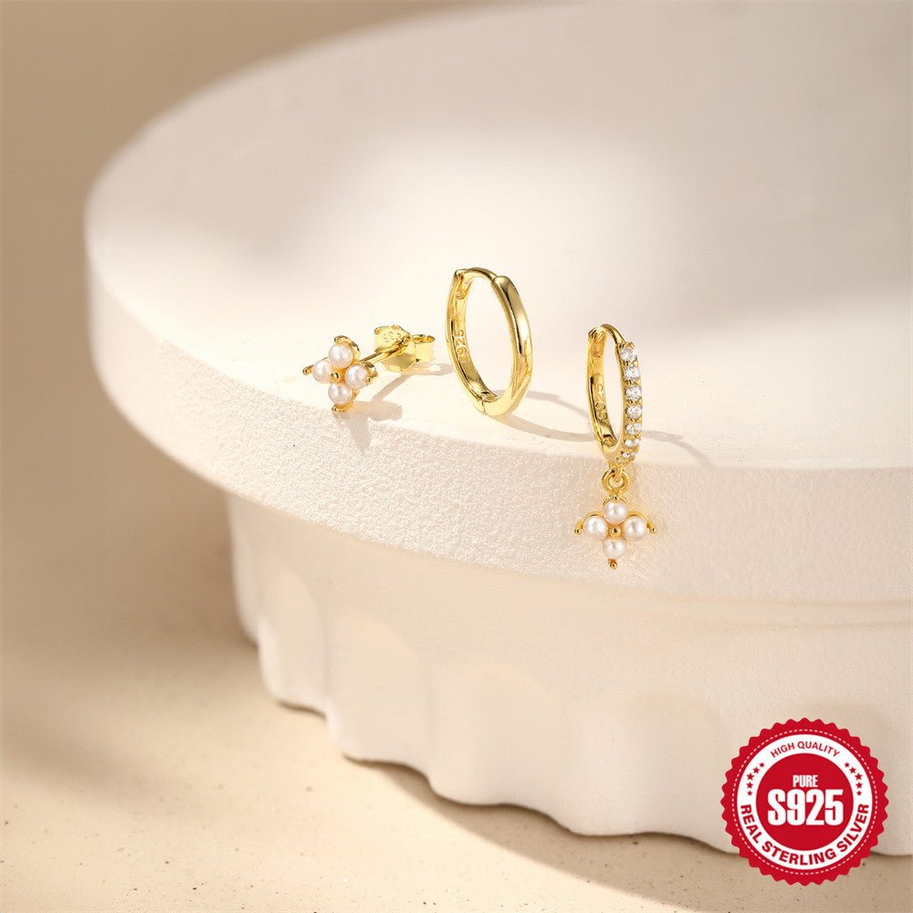 mixed floral stud and hoop earrings arranged on a cream display