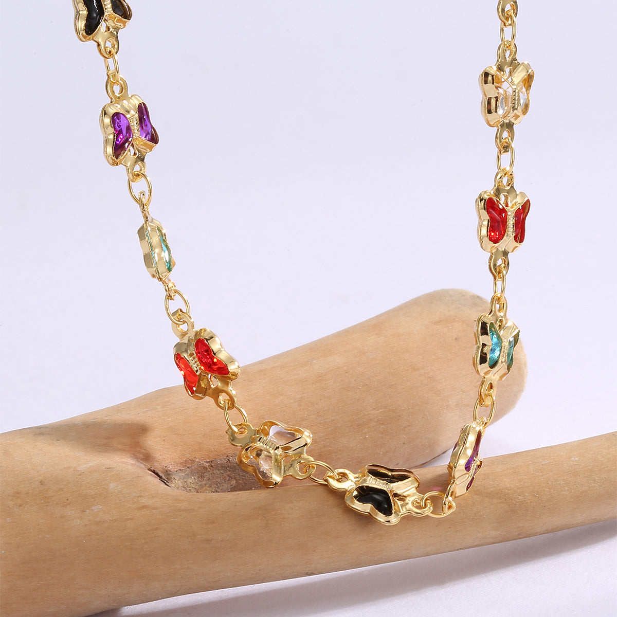 gold plated butterfly necklace displayed over a natural wood branch