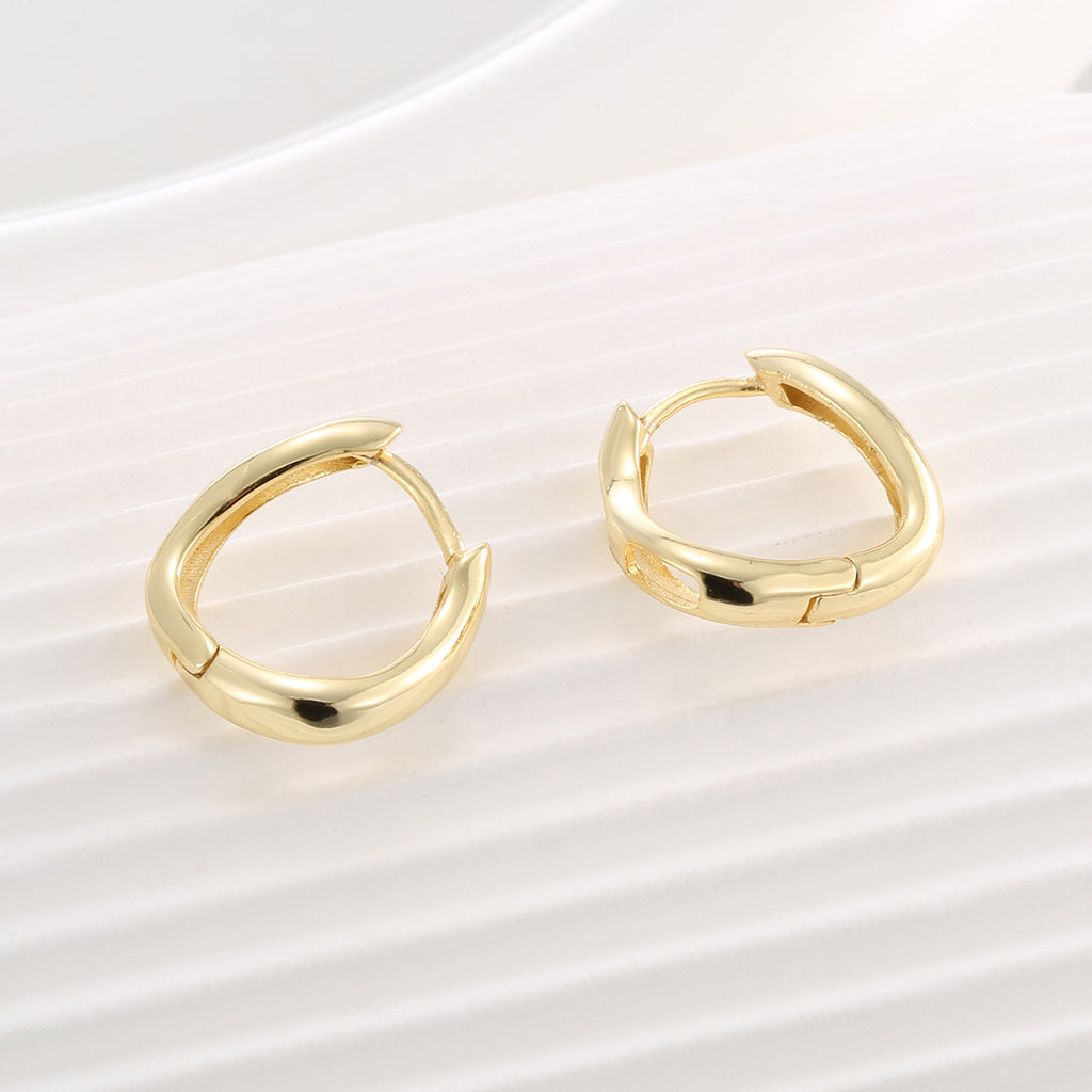 pair of sculptural hinged huggie hoops on a pale surface