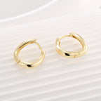 pair of sculptural hinged huggie hoops on a pale surface
