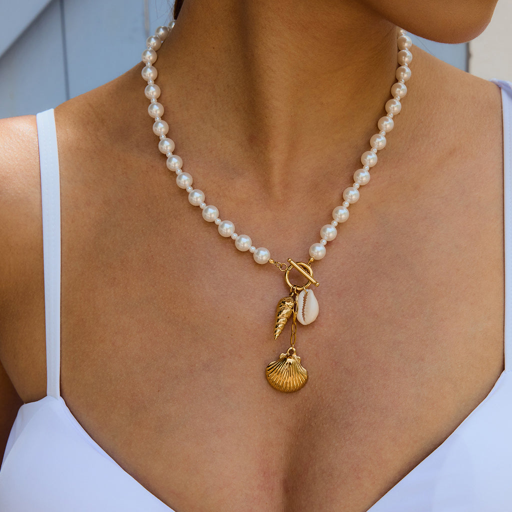 Shell charm and white bead necklace worn with a blue top