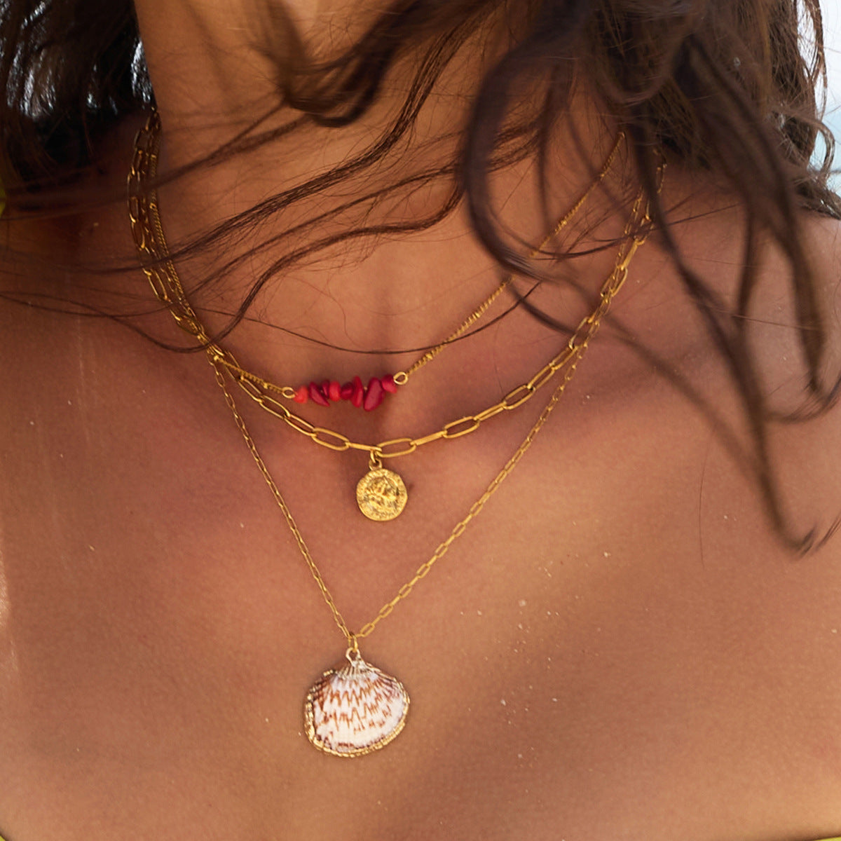 Shell pendant necklace with red beads and coin layer worn by model