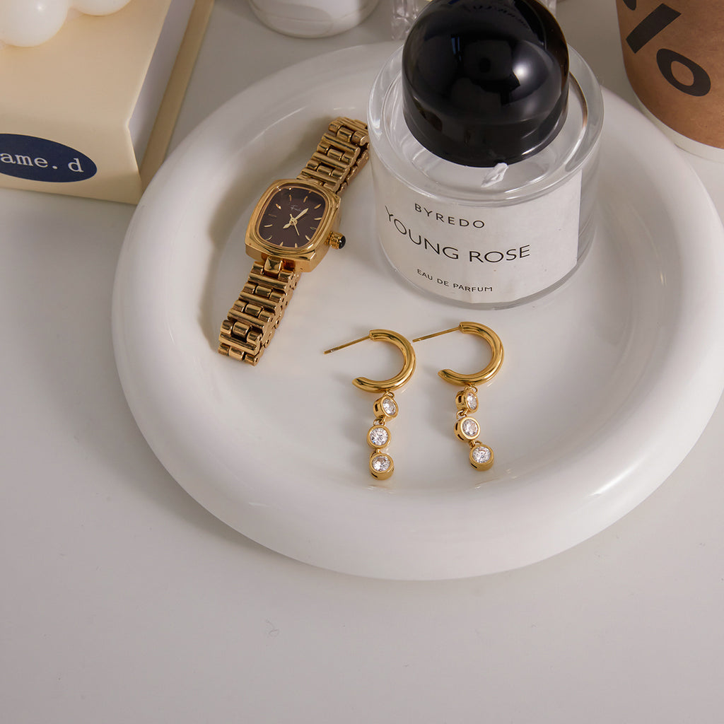 pair of gold plated drop hoops styled on a tray