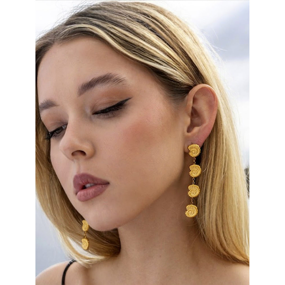 Model wearing reference shell earrings from the same visual theme