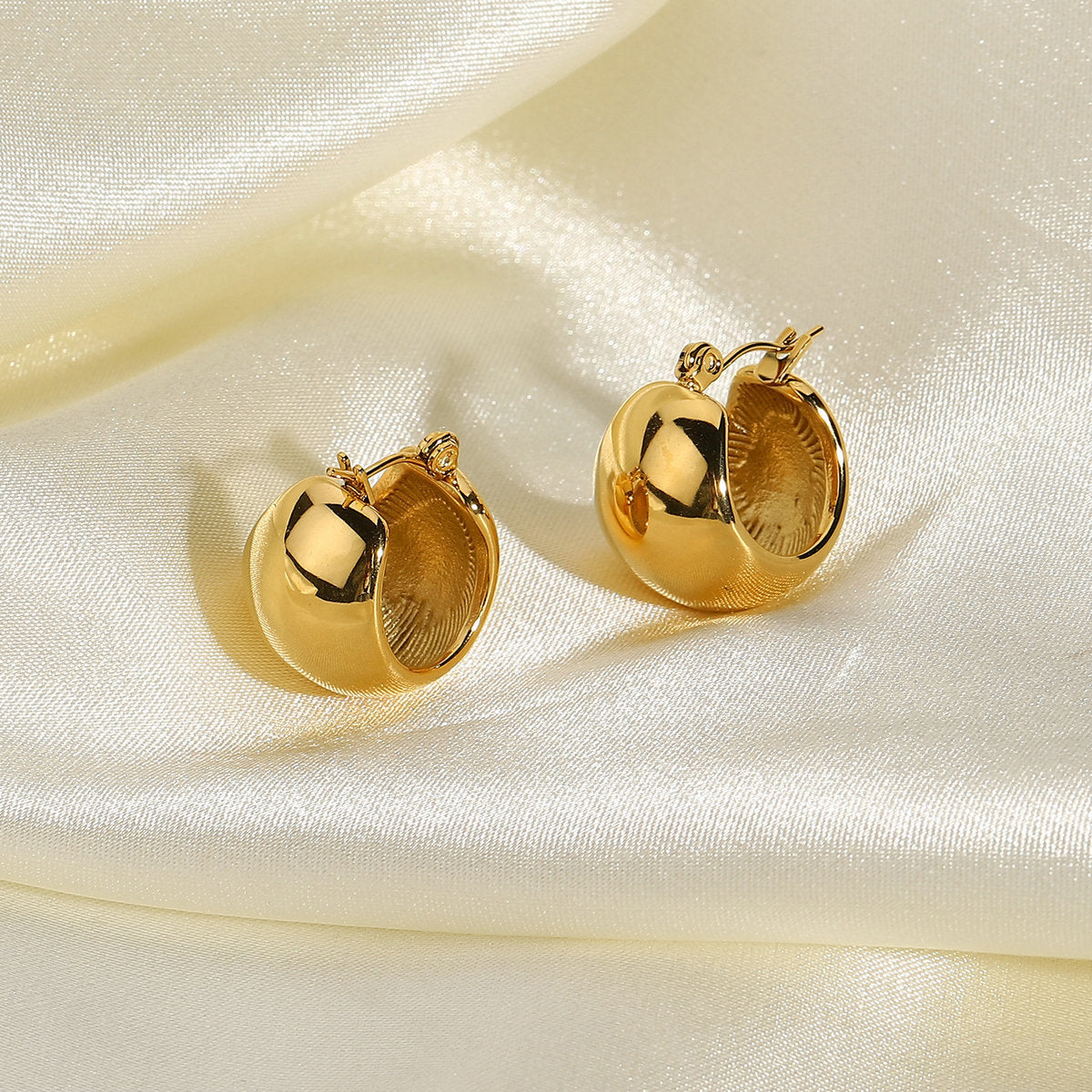 rounded gold plated stainless steel huggies styled on satin