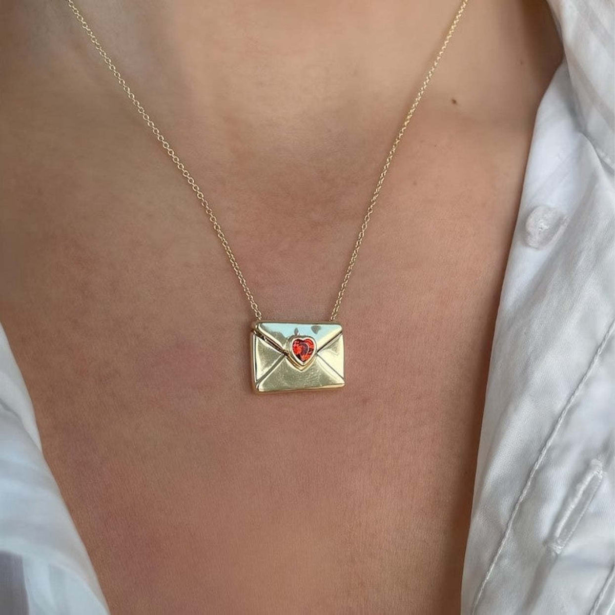 closed envelope pendant necklace with a red heart-shaped stone