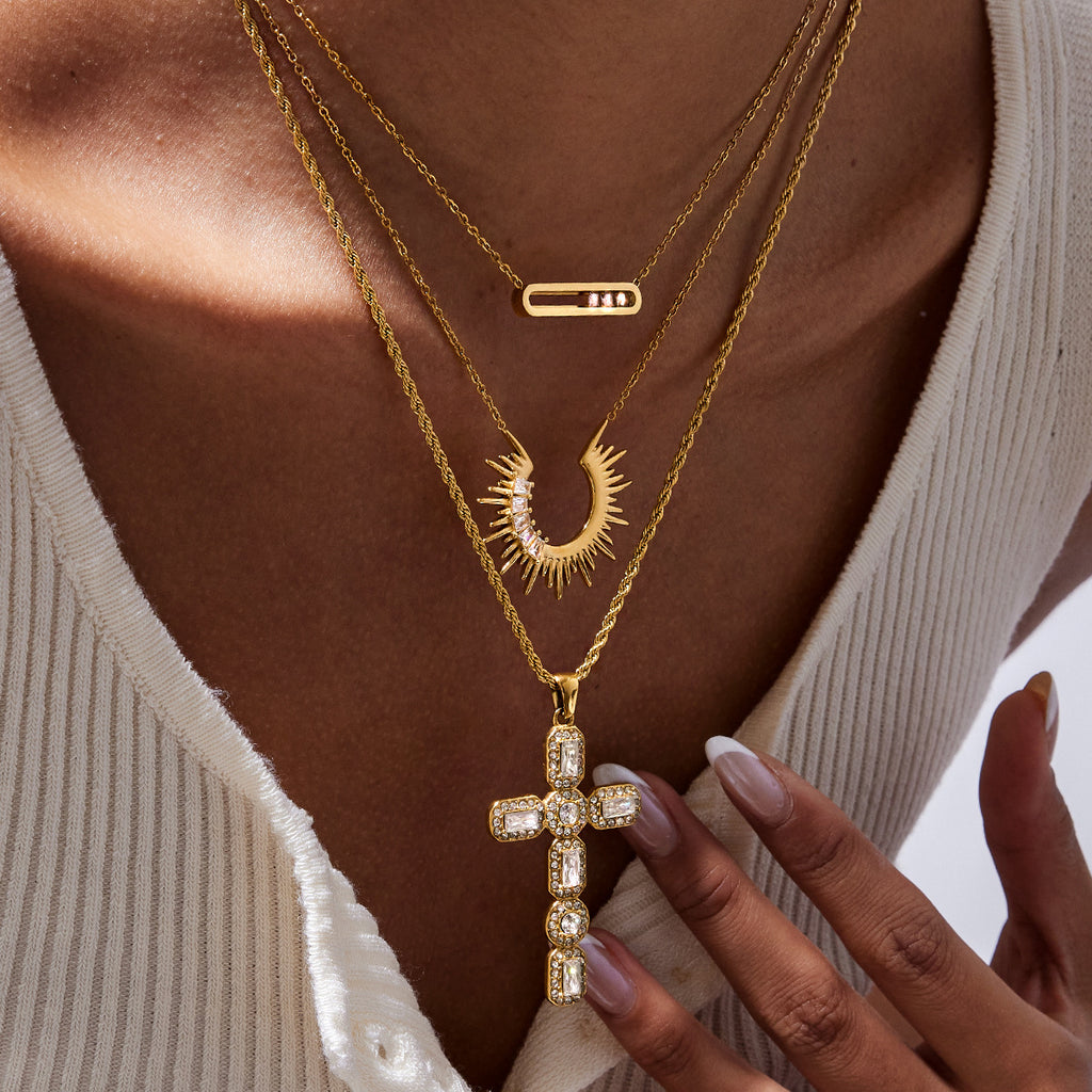 Layered gold-tone necklaces worn with an accent-set cross pendant