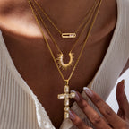 Layered gold-tone necklaces worn with an accent-set cross pendant
