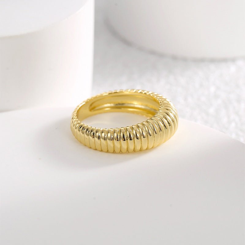 angled gold plated ribbed dome ring on a pale display
