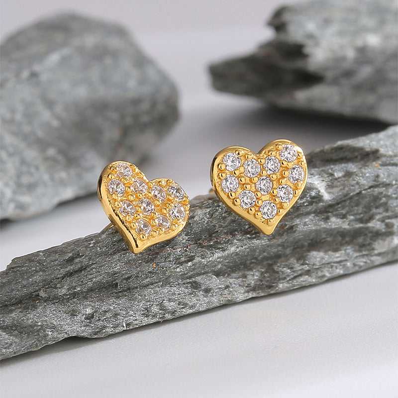 pair of gold plated pavé heart earrings on layered rock