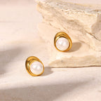 pair of pearl stud earrings in asymmetrical polished metal cradles